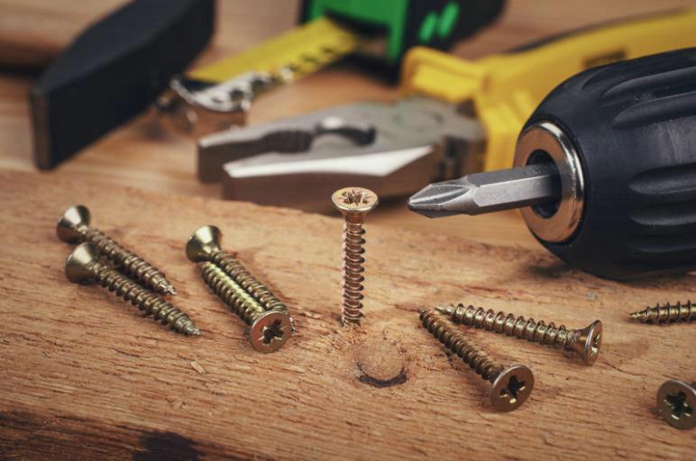 Parafusos e ferramentas sobre madeira.