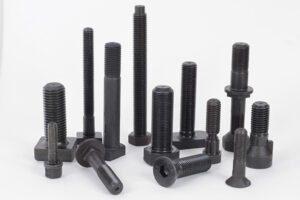 Parafusos industriais de diferentes tamanhos em fundo branco.